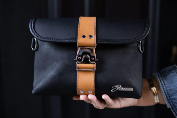 Woman holding the black and tan Little Sister leather handbag from Swagger Leather.