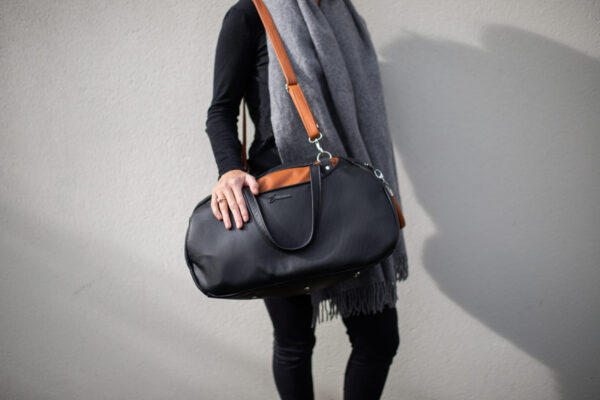 woman standing holding the Travel Bag from Swagger leather.